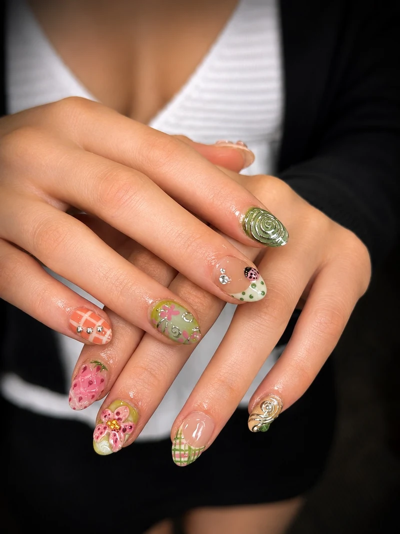 Green and pink nail art with flowers, a strawberry, swirls and checked tips
