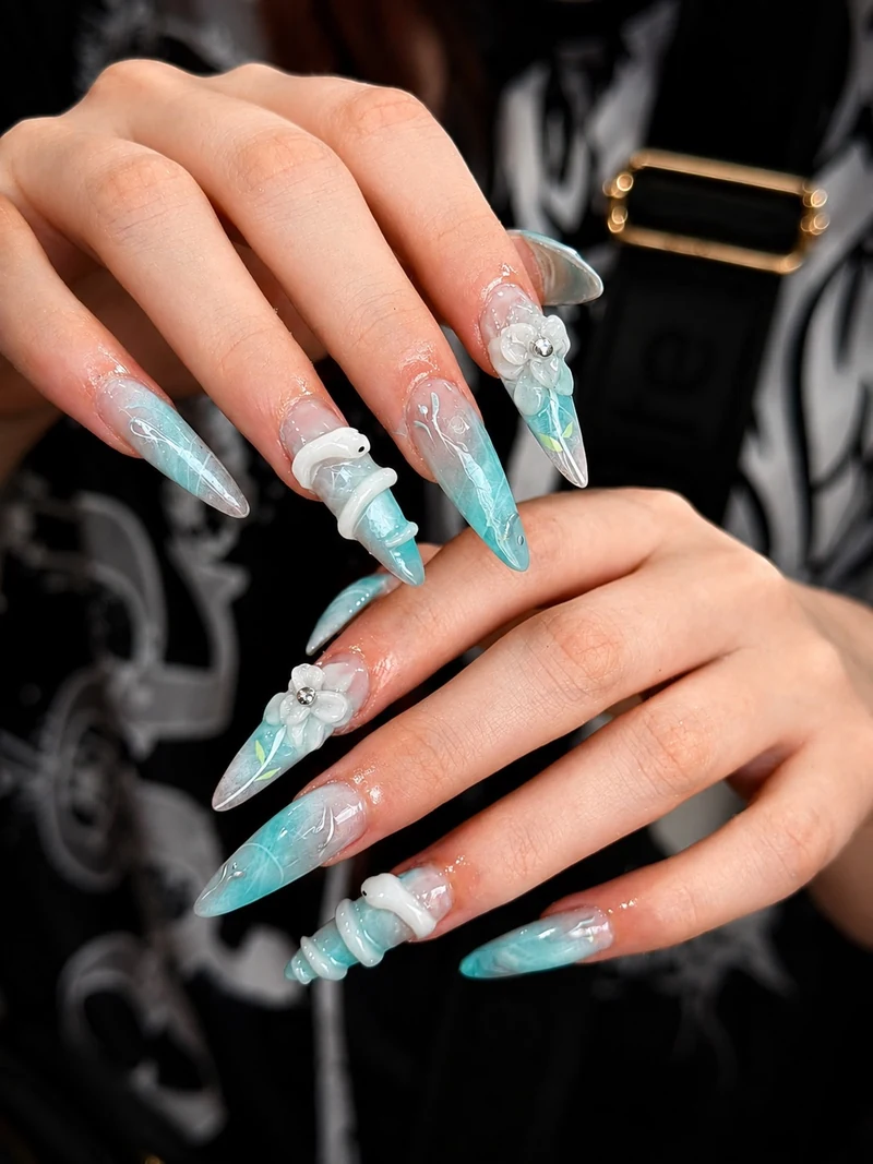Turquoise stiletto nails with sculpted white flowers and spiral details