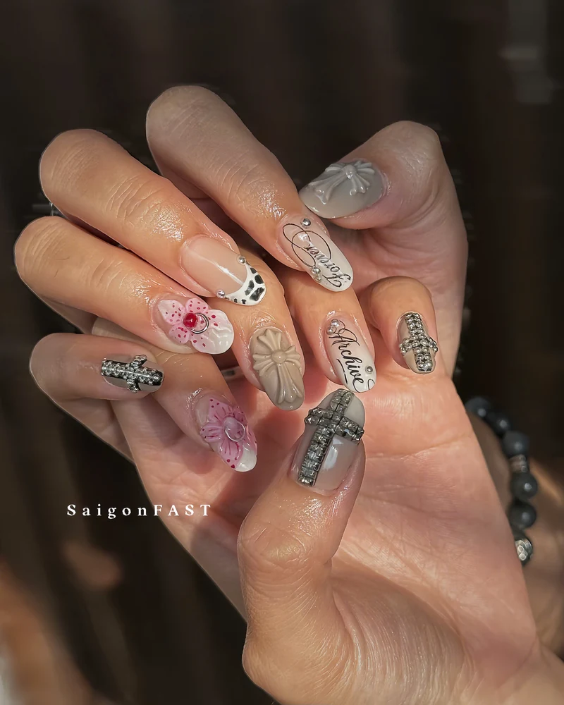 Nude and grey nail art with pink flowers, bows and jeweled cross embellishments