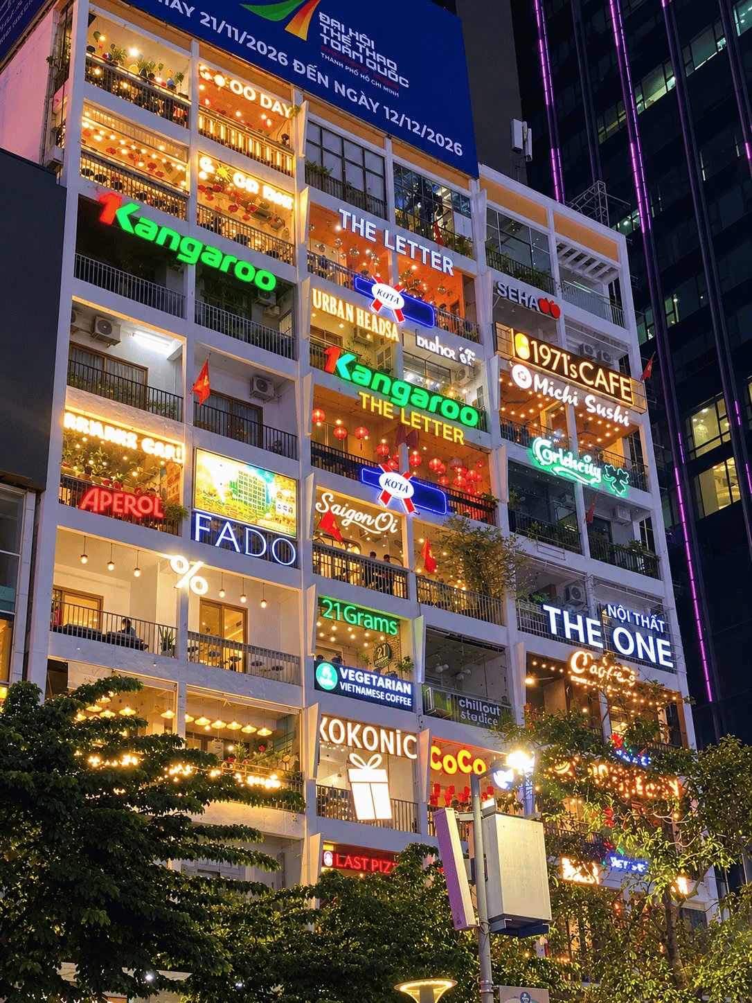 The illuminated Café Apartment façade at night